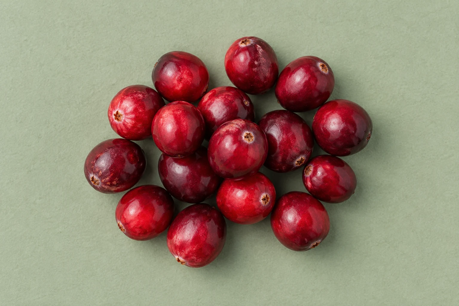 Whole red cranberries on a sage-green surface
